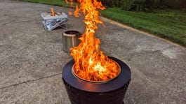 A black fire pit with a large flame, and two other fire pits in the background.