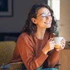 Woman smiling and relaxing while drinking tea.