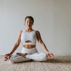 A woman doing a yoga pose on a tan carpet