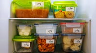 Food leftovers packaged in boxes inside a home fridge with dates written on.