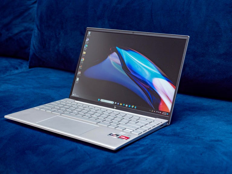 The 2023 HP Pavilion Aero 13 laptop open and facing to the right and sitting on a dark blue couch.